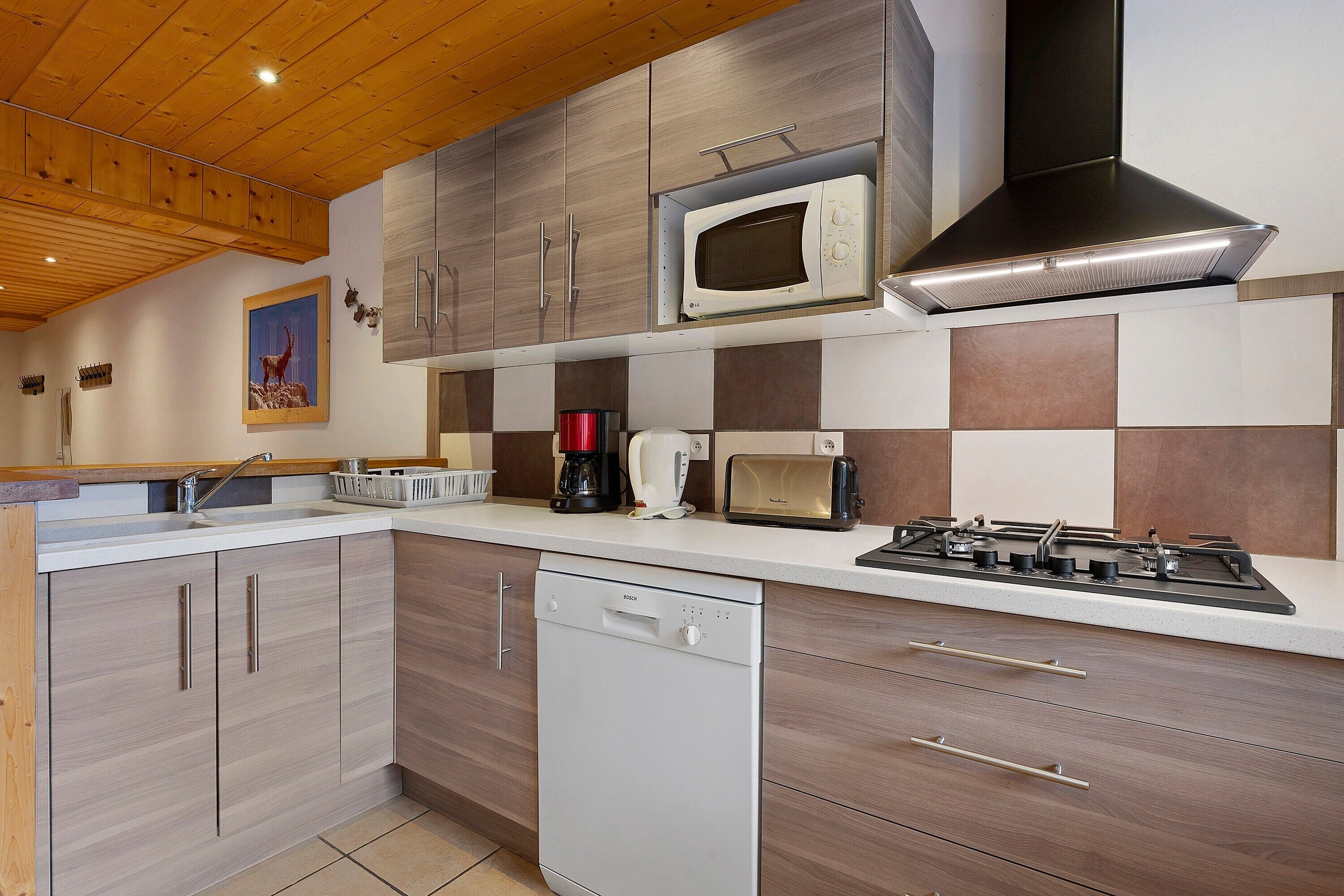 A modern kitchen with wooden cabinets, a microwave, a toaster, a coffee maker, and a dishwasher.