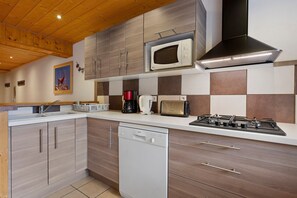 Eine moderne Küche mit Holzschränken, einer Mikrowelle, einem Toaster, einer Kaffeemaschine und einem Geschirrspüler.