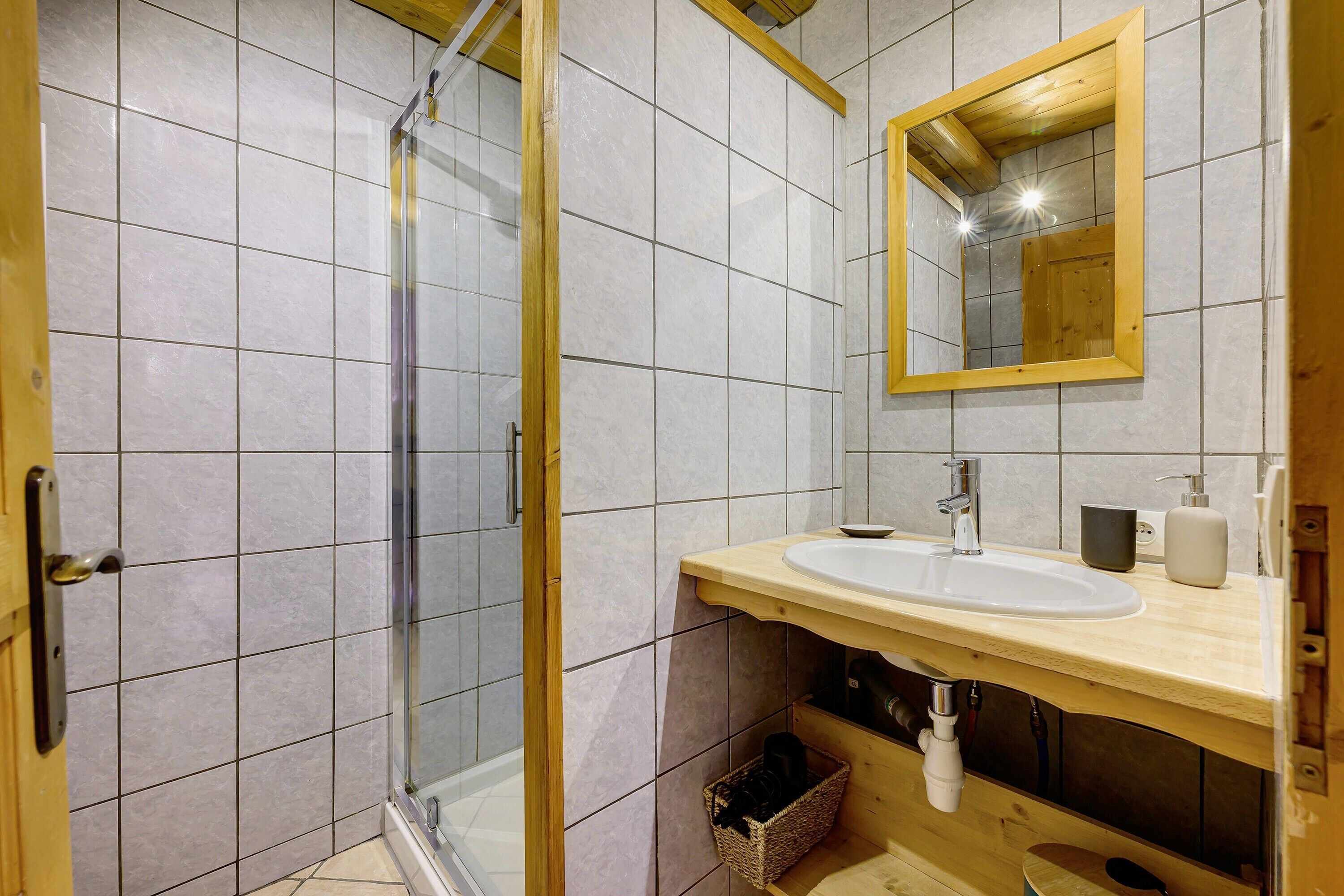 Une salle de bain avec une douche à parois de verre, un meuble-lavabo en bois et un miroir.