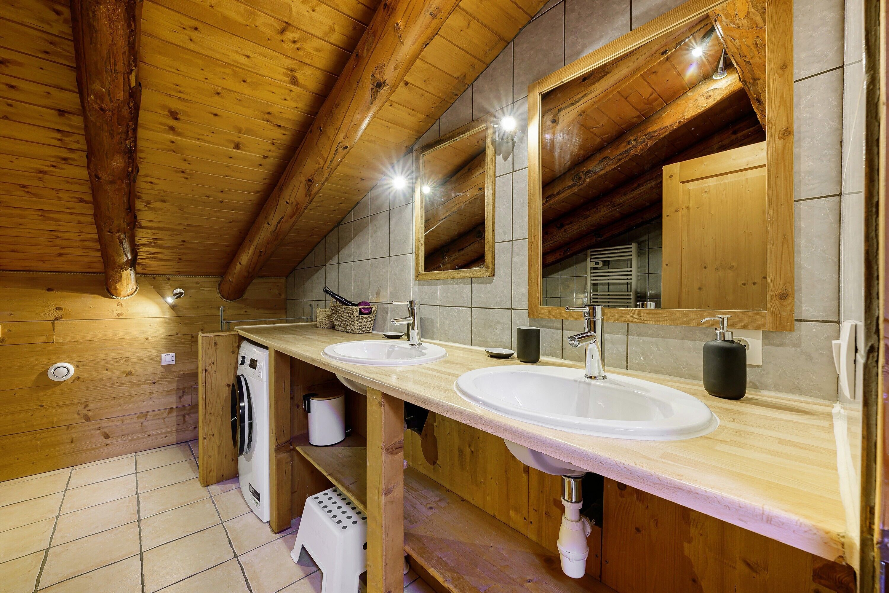 A wooden cabin bathroom with two sinks, a mirror, and a washing machine.