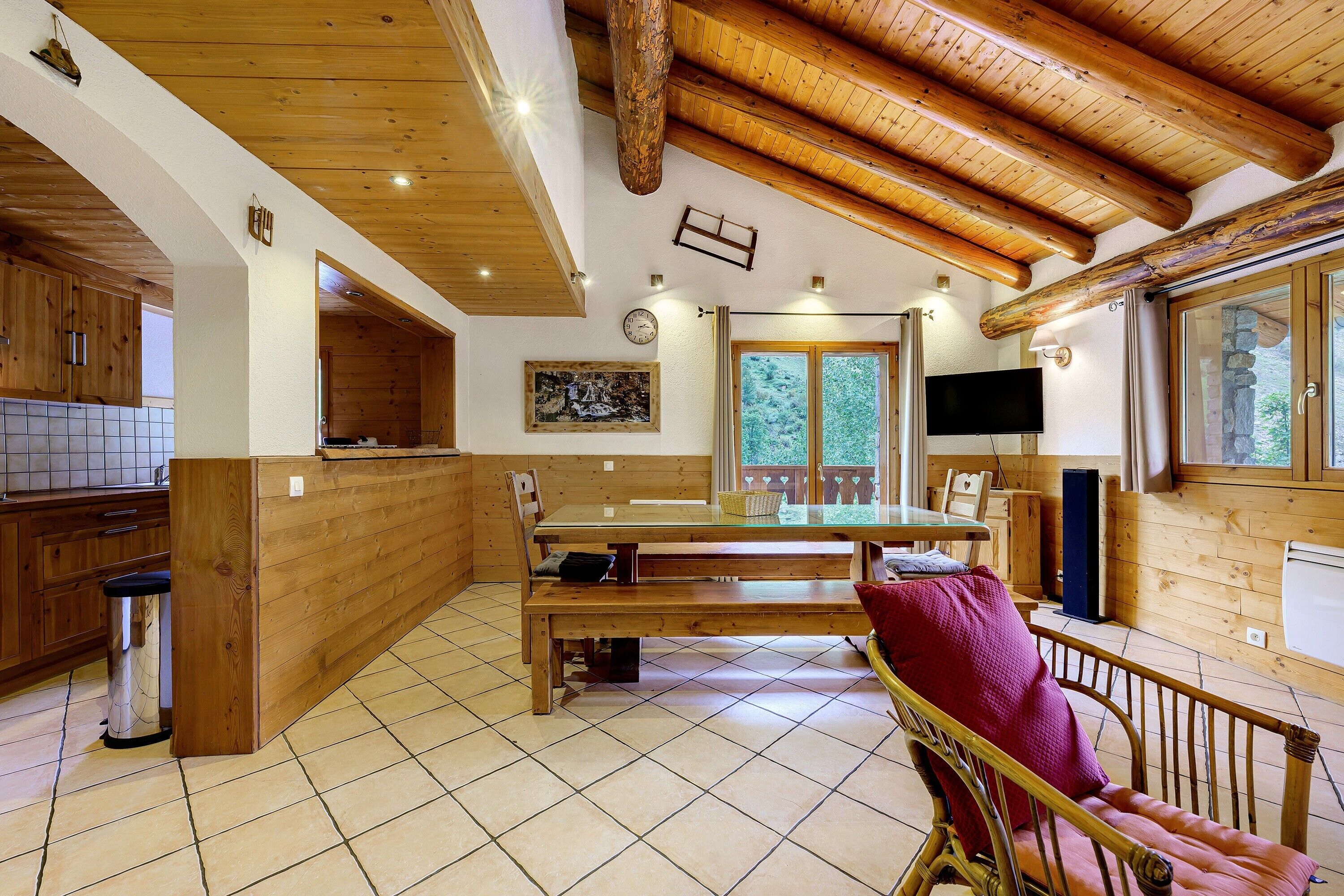 A wooden interior with a kitchen, dining area, and a TV.