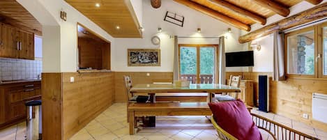 A wooden interior with a kitchen, dining area, and a TV.