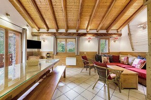 Ein Zimmer mit Holzboden, einem Glastisch, einer Couch mit Kissen und einem Fernseher.