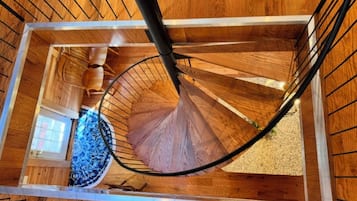 Un escalier en colimaçon avec des marches en bois et des rampes en métal, menant à l’étage supérieur.