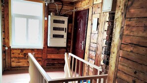 Un intérieur en bois avec un escalier, une fenêtre et des panneaux électriques.