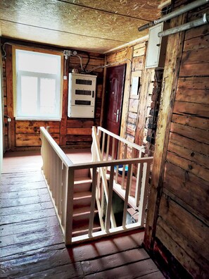 A wooden interior with a staircase, a window, and electrical panels.