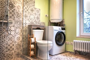 Un bagno con piastrelle decorate, un water, una lavatrice e un termosifone.