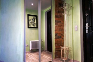 A hallway with a glass door, a radiator, a framed artwork, a brick wall, and a door with a handle.