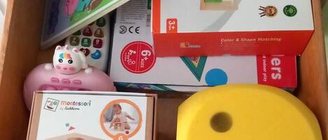 A drawer containing various children's toys and educational materials, including a Montessori toy, a color and shape matching game, and a puzzle.
