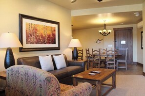 A living room with a sofa, armchair, coffee table, and dining area with chairs and a wooden table. - Beautiful 2 bedroom/bath condo at Grand Lodge on Peak 7 for Oct. 3 - 10! (Breckenridge)
