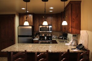 A kitchen with granite countertops, wooden cabinets, stainless steel appliances, and pendant lighting. - Beautiful 2 bedroom/bath condo at Grand Lodge on Peak 7 for Oct. 3 - 10! (Breckenridge)