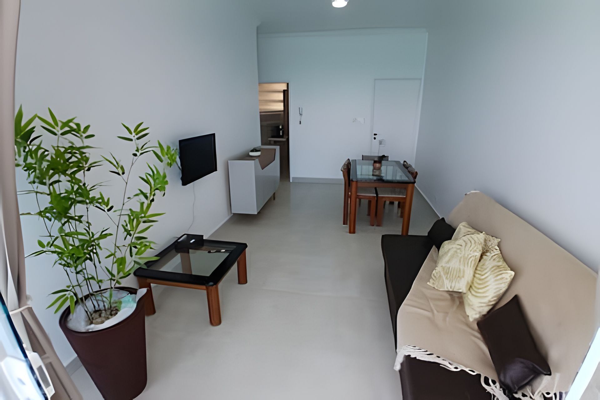 Una sala de estar moderna con un sofá, una mesa de centro, un televisor y un comedor con mesa y sillas.