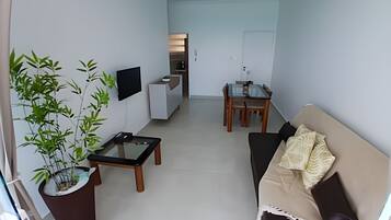 Una sala de estar moderna con un sofá, una mesa de centro, un televisor y un comedor con mesa y sillas.