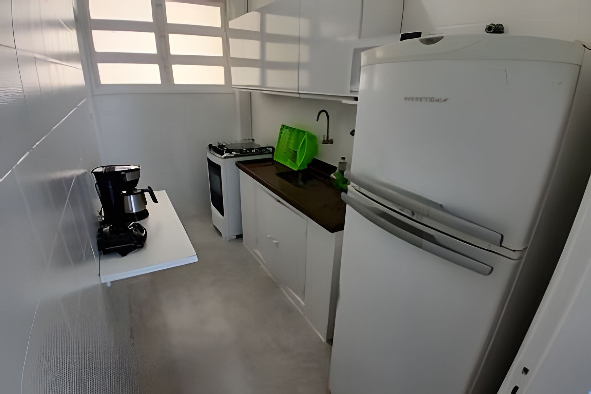 A compact kitchen with white cabinets, a coffee maker, a stove, and a refrigerator.