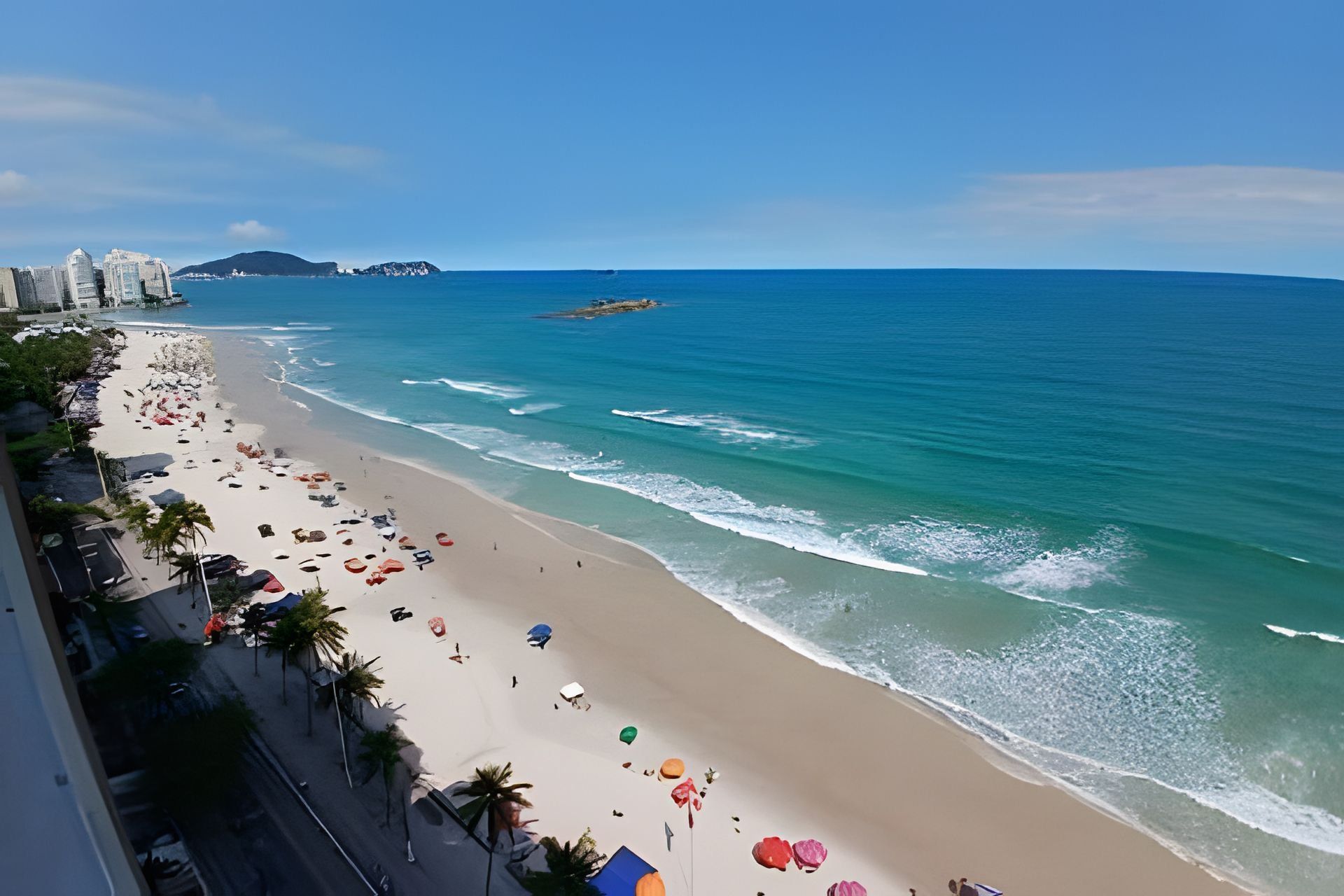 A beach with a clear view of the ocean, a sandy shore, and a distant mountain.