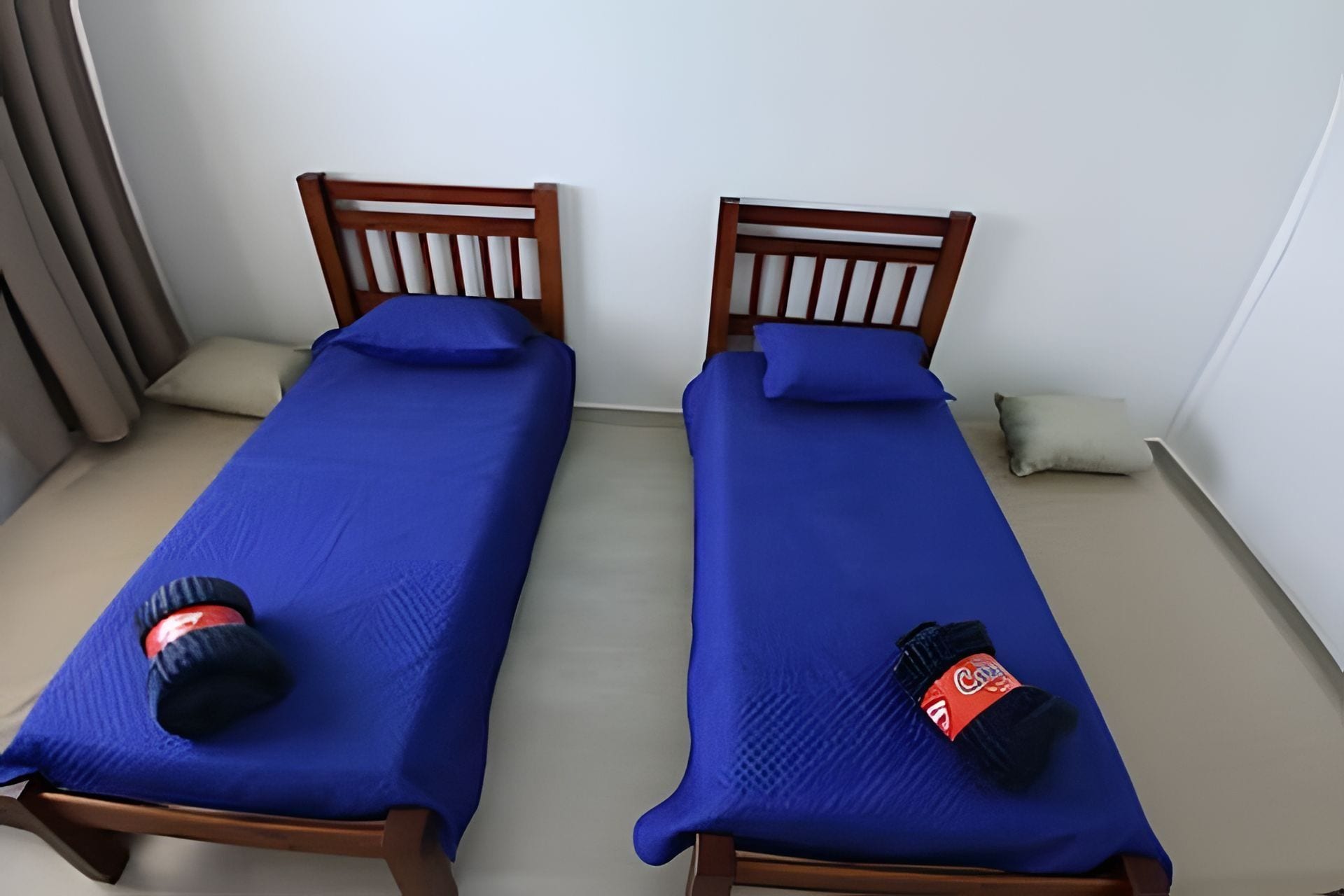 Dos camas individuales con estructura de madera y ropa de cama azul.