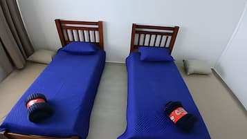 Dos camas individuales con estructura de madera y ropa de cama azul.