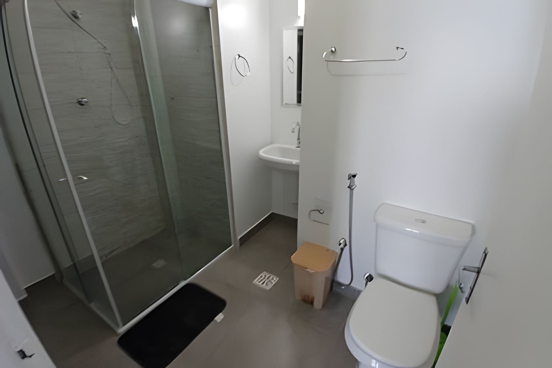 A bathroom with a glass shower enclosure, a white sink, and a toilet.
