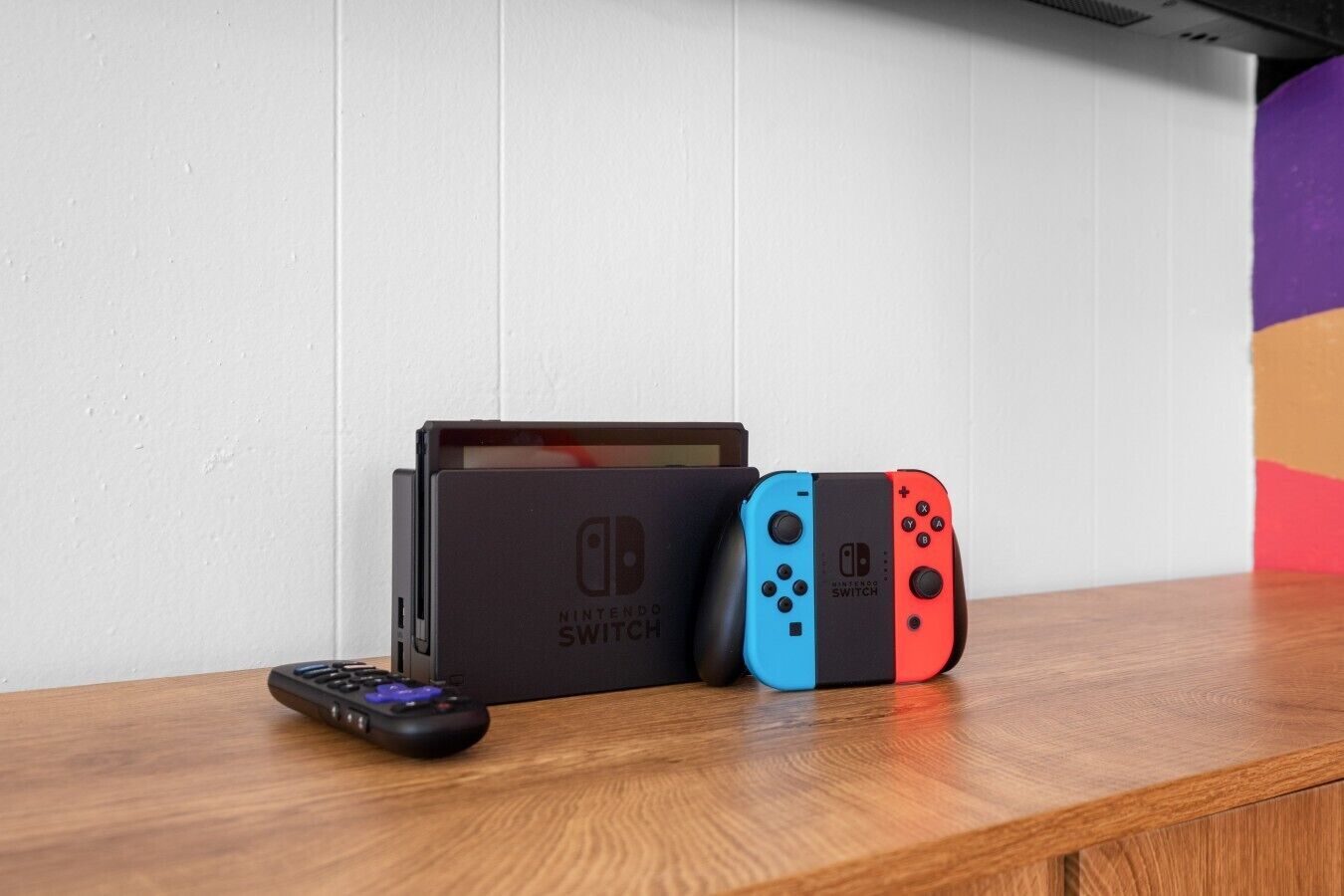 A Nintendo Switch console and two controllers on a wooden surface.