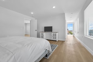 A bedroom with a bed, a TV on a cabinet, and a view of the outside.
