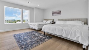 Ein Schlafzimmer mit zwei Betten, einem großen Fenster und Blick auf die Stadt.