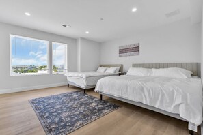 Ein Schlafzimmer mit zwei Betten, einem großen Fenster und Blick auf die Stadt.