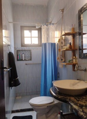 Baño con inodoro, lavamanos, cortina de ducha y ventana.