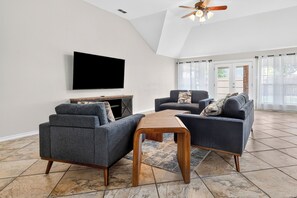 Ein modernes Wohnzimmer mit Flachbildfernseher, zwei Sofas, einem Couchtisch und einem Deckenventilator.