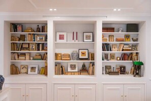 Ein Zimmer mit drei weißen Regalen, gefüllt mit Büchern, gerahmten Bildern und Dekoration.