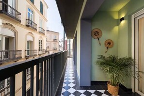 Ein Korridor mit Schachbrettboden, einem Balkon mit Geländer und einem Blumentopf.