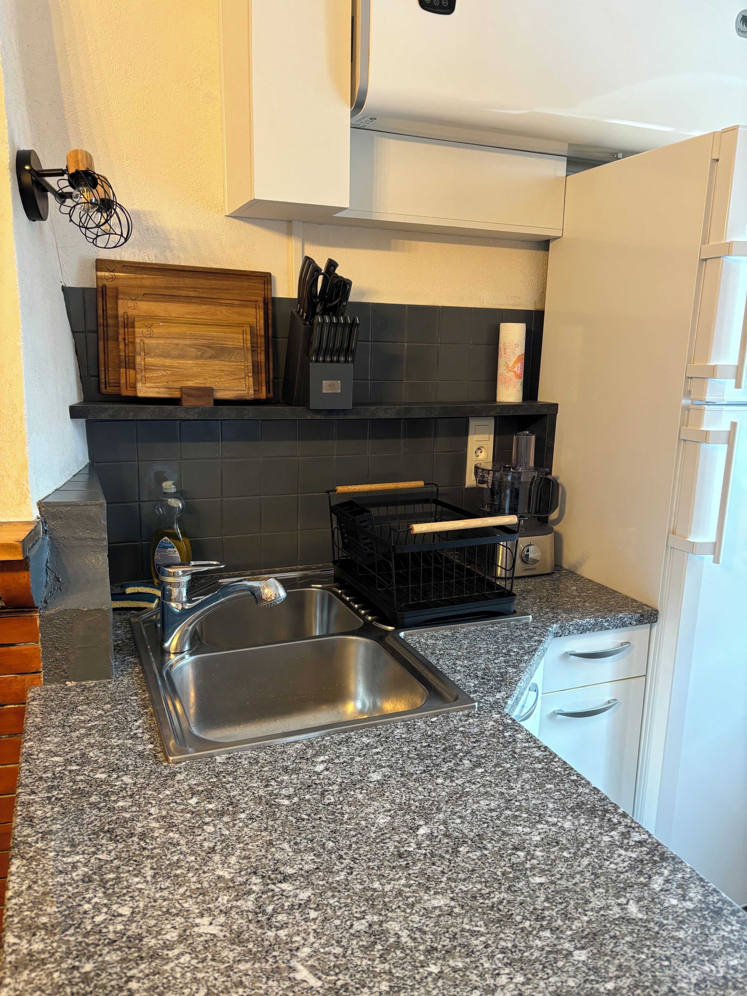 Cocina con encimera de granito, pileta de acero inoxidable y cestas de almacenamiento negras.