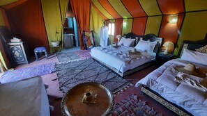 A tent-style room with two beds, a small table, and a hanging chair. - Authentic Sahara Desert Camp in Mhamid - Peaceful andUnforgettables Stay (Mhamid)