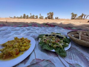 A meal set on a table outdoors with a desert landscape in the background.