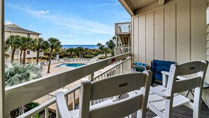A balcony with white chairs, a pool, and a view of the ocean. - Breakers 220 Oceanfront Condo Direct Beach Access Elevator (Hilton Head Island)