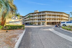 Un hotel de varios pisos con un letrero que indica que es propiedad privada, sin acceso a la playa y un estacionamiento con vehículos.