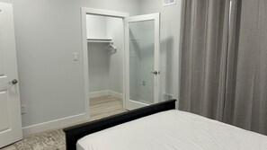 A bedroom with a bed, a wardrobe, and a walk-in closet.