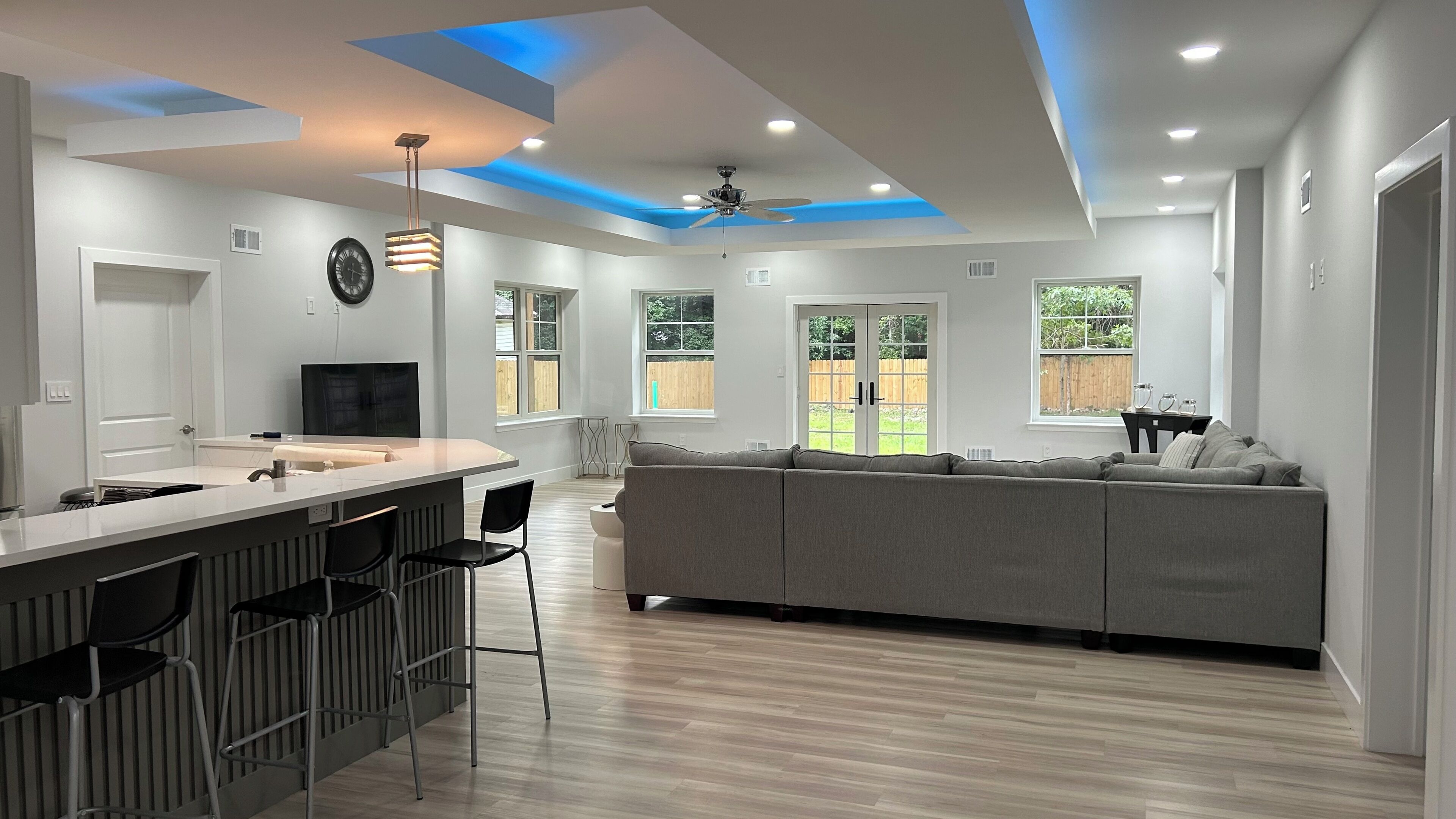 Eine moderne Küche mit Barbereich, einem grauen Sofa und einem Deckenventilator.