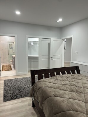 Ein Schlafzimmer mit Bett, begehbarem Kleiderschrank und einem Badezimmer mit Dusche und Toilette.