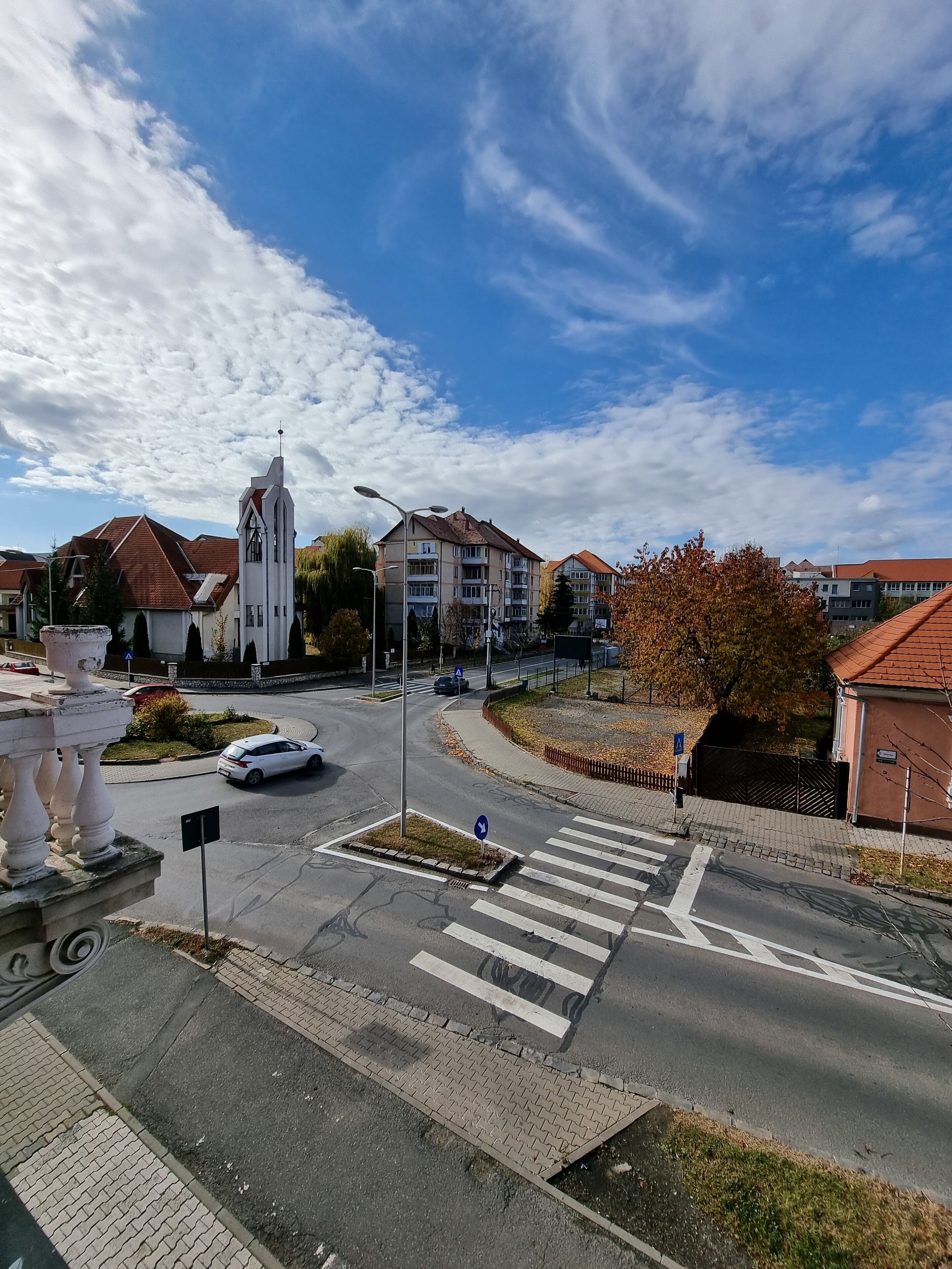 A street view with a church, residential buildings, and a pedestrian crossing.