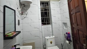 A bathroom with a toilet, sink, mirror, and a water heater.