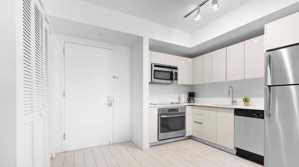 A modern kitchen with white cabinetry, stainless steel appliances, and a built-in oven. - Intracoastal 2BR - Pool, Resort & Private Balcony (Hallandale Beach)