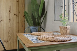 Une table avec un set de table en fibres tressées, une plante en pot et une chaise.