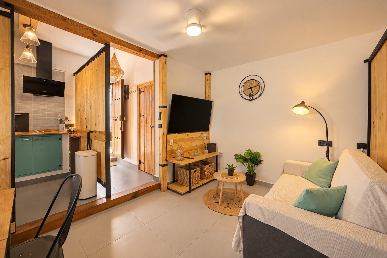 Een moderne woonkamer met een bank, een televisie en een eethoek met een tafel en stoelen.