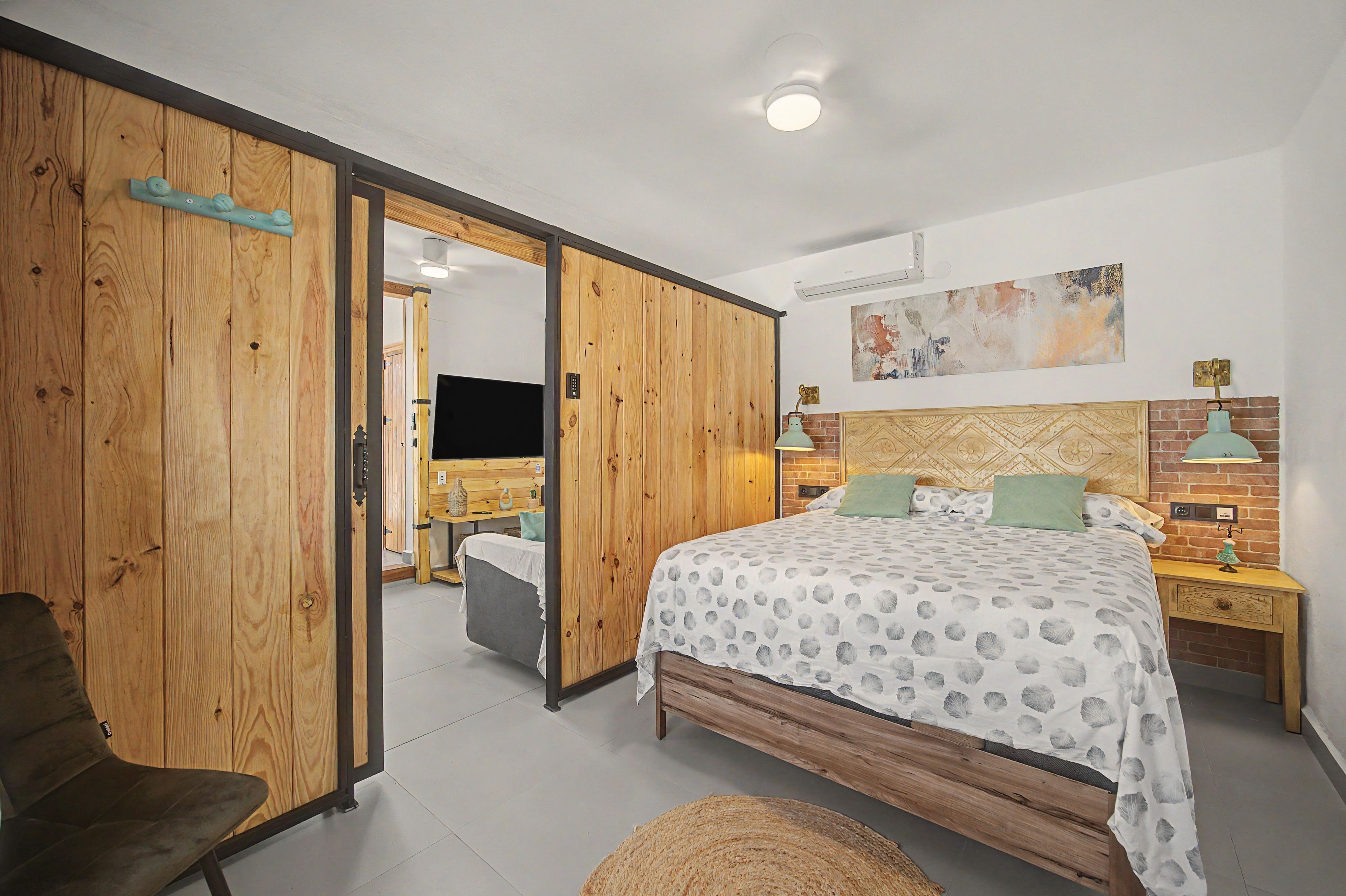 Een slaapkamer met een bed, nachtkastje, lamp, stoel en een kledingkast.