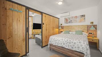 Een slaapkamer met een bed, nachtkastje, lamp, stoel en een kledingkast.