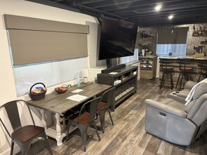 A modern living room with a wooden dining table, dark chairs, a gray sofa, and a flat-screen TV mounted on the wall. - Charming apartment in awesome Louisville with cool AC breeze (Louisville)
