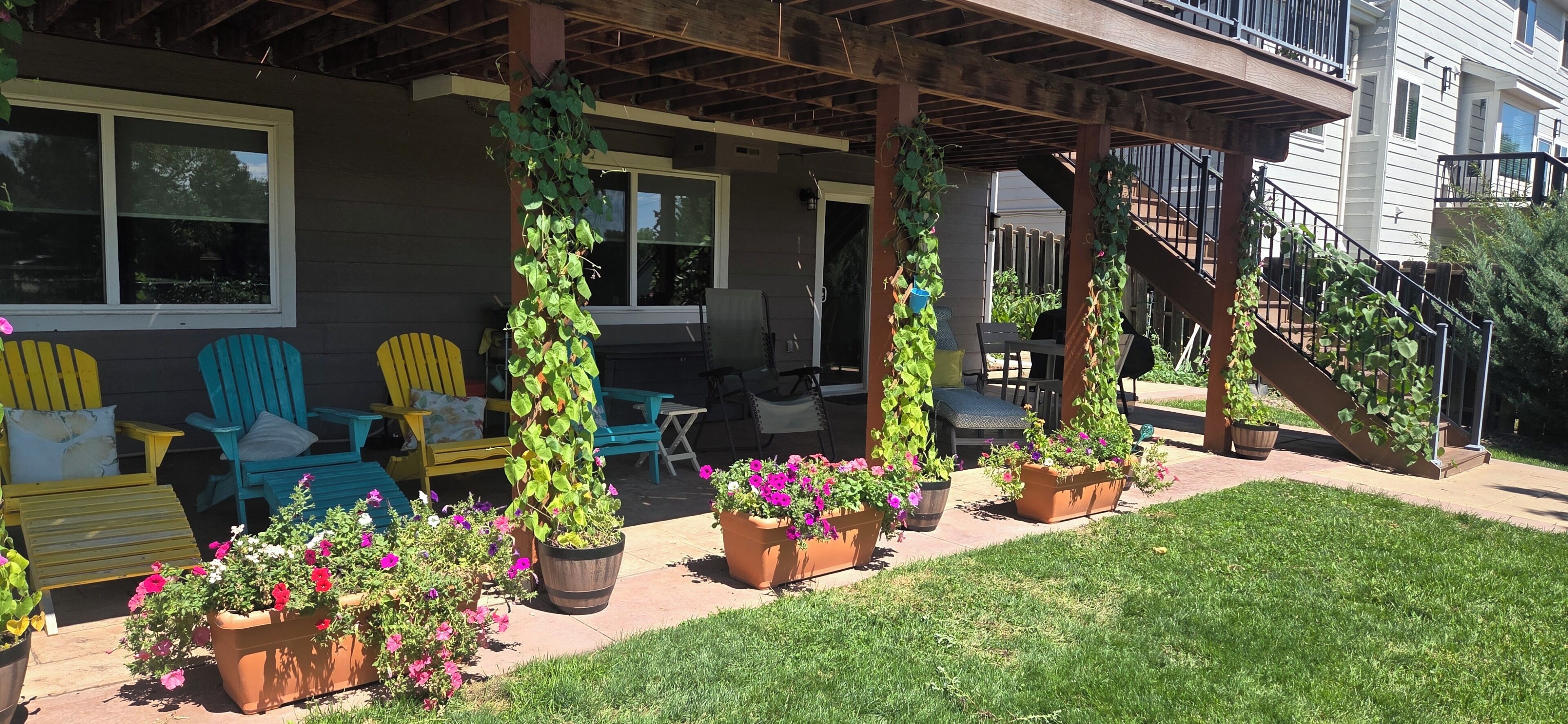 A covered patio with outdoor seating, potted plants, and a staircase leading to a second floor.
