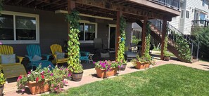 Eine überdachte Terrasse mit Sitzgelegenheiten im Freien, Topfpflanzen und einer Treppe zu einer zweiten Etage.