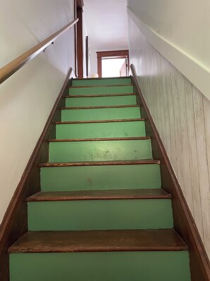 Un escalier avec des marches vertes et des rampes en bois menant à l’étage supérieur.