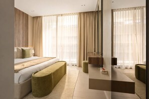 Habitación de hotel moderna con cama, banca, una mesita y espejo.
